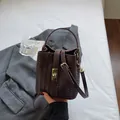 Deep brown woven bucket bag with golden metal clasp and adjustable shoulder strap - Coffee