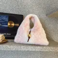 Pink and white fuzzy faux fur handbag featuring a gold ball charm and stone background - Pink