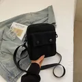 Black canvas crossbody bag with dual buttons and adjustable strap in a lifestyle setting - Black