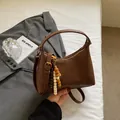 Retro brown faux leather shoulder bag with vintage wooden beads on white bedding - Brown