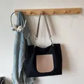 Minimalist black tote bag with beige pocket and silver chain straps in lifestyle setting - Black