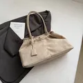 Minimalist beige frosted leather tote bag with shoulder strap shown on grey suit blazer - Beige Grey