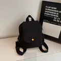 Minimalist black mini canvas backpack with a bright yellow round buckle detail - Black