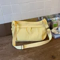 Close-up of yellow nylon crossbody bag with dual drawstring zipper pockets on a table - Yellow