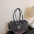 Dark gray washed denim tote bag with metallic logo plate on a magazine background - Black
