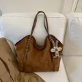 Detailed view of brown suede tote bag with a cute plush bunny charm on a soft sofa - Brown with Pendant