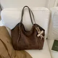 Detail of suede tote bag in brown with long-eared rabbit charm on a white sofa - Brown with Pendant
