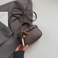 Bolso bandolera de cuero marrón con colgante de cuentas de madera y texto en relieve - Café Con Colgante