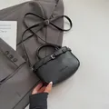 Minimalist black leather crossbody bag with buckle detail on a grey suit background - Black without Pendant