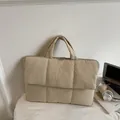 Beige quilted laptop tote bag with dual handles for women, shown in a minimalist office setting - Off-white