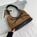 Bolso hobo de ante marrón con adornos de cuero negro y lazo sobre atuendo de mezclilla - Marrón