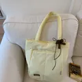 Pale yellow quilted tote bag with brown bows and dual front pockets for women - With Pendant / Yellow