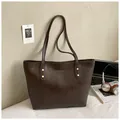 Borsa tote marrone caffè in pelle PU con borchie dorate e logo su scrivania moderna - Marrone