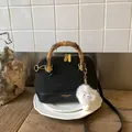 Detail of black patchwork shell bag featuring bamboo handle and plush eye charm - Black With Pendant