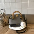 Close-up of leopard shell bag with bamboo handle and plush monster charm detail - Grey With Pendant