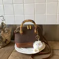 Detail of leopard print拼接 shell bag with bamboo handle and plush monster charm - Brown with Pendant