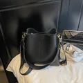 Moderna borsa a secchiello in pelle nera con ampia tracolla in tessuto e dettagli oro - Nero