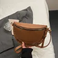 Brown half-moon crossbody bag with gold studs on a minimalist lifestyle setting - Khaki