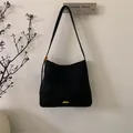 Detail shot of black matte leather tote bag featuring elegant gold metal hardware buckle - Black