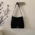 Detail of black frosted tote bag featuring a textured finish and golden oval metal emblem - Ebony
