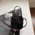 Bolso tipo cubo de ante negro con flecos largos y herrajes de metal dorado elegante - Negro