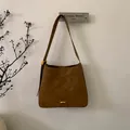 Detail of caramel lychee leather texture and golden metal hardware on a vintage tote bag - Brown