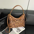Leopard print crossbody bag with brown leather straps on a black leather sofa - Leopard Brown No Pendant