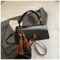 Fashionable black cylindrical underarm bag with knot handle and brown fringe charms - With Charm / Black