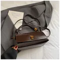 Dark brown underarm bag with gold turn-lock and woven handle on a vintage background - No Pendant / Brown