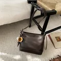 Détail d'un sac à bandoulière en cuir mat marron foncé avec un pendentif baseball créatif - Avec Pendentif / Marron