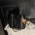 Black suede tote bag with golden chain strap and fashion accessories in lifestyle setting - With Charm / Black
