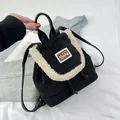 Detail of mini black corduroy backpack with fleece trim and bear patch on white fabric - Black