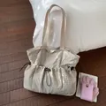 Detail van beige geruite canvas shopper met trekkoordsluiting op donkere houten vloer - Off-wit