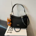 Schwarze Hobo-Tasche aus Wildleder mit weißen Nähten und dekorativem Bärenanhänger - Schwarz Mit Anhänger