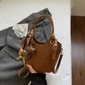 Detail of vintage brown bucket bag with star charm and teddy bear pendant on white bedding - With Pendant / Brown