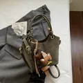 Detail of olive green bucket bag with star charm and teddy bear on a bed - With Pendant / Green