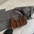 Bolso medialuna de ante marrón oscuro con ribete de cuero y cadena de metal dorado - Café