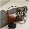Dunkelbraune glänzende Boston-Tasche aus Leder mit dekorativen Anhängern und Schultergurt - Mit Anhänger / Braun