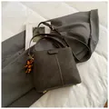 Borsa a secchiello marrone caffè opaca con nappa di perline di legno su blazer grigio - Marrone