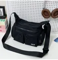 Détail d'un sac bandoulière noir avec multiples poches zippées et logo blanc DDX - Noir