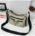 Détail du sac bandoulière en nylon beige avec plusieurs poches zippées et logo DDX - Khaki