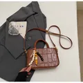 Dunkelbraune Handtasche mit Krokoprägung, Perlenquaste und verstellbarem Schultergurt - Mit Anhänger / Gelbbraun
