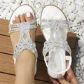Detail of white bohemian flat sandals with crystal embellishments on white pebbles - White
