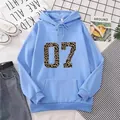 Detail view of light blue hoodie featuring leopard print number 07 and kangaroo pocket - S / Sky Blue