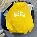 Flat lay of yellow hooded sweatshirt with white Boston lettering and lifestyle props - Yellow