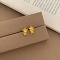 Matte gold floral double-flower stud earrings with textured finish on display stand - Golden Double Five Petal Flower