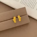Golden flower stud earrings with three-petal linear design on dark velvet display - Golden Triple Five Petal Flower