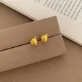 Matte gold apple-shaped stud earrings with leaf detail on a brown velvet display - Golden Brushed Apple Stud Earrings