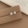 Minimalist silver matte apple-shaped stud earrings displayed on a beige velvet stand - Silver Brushed Apple Stud Earrings