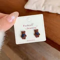 Cute brown flocked bear earrings with blue scarf detail on white display card - Coffee Bear (Blue Scarf)